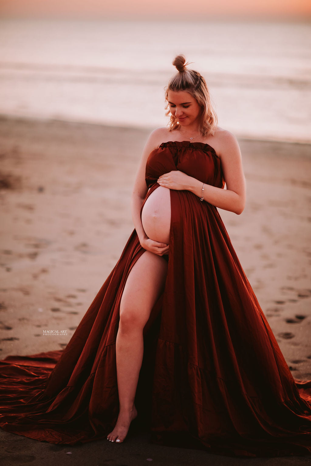 Pregnant lady wearing brown satin dress for a maternity photoshoot at the beach.